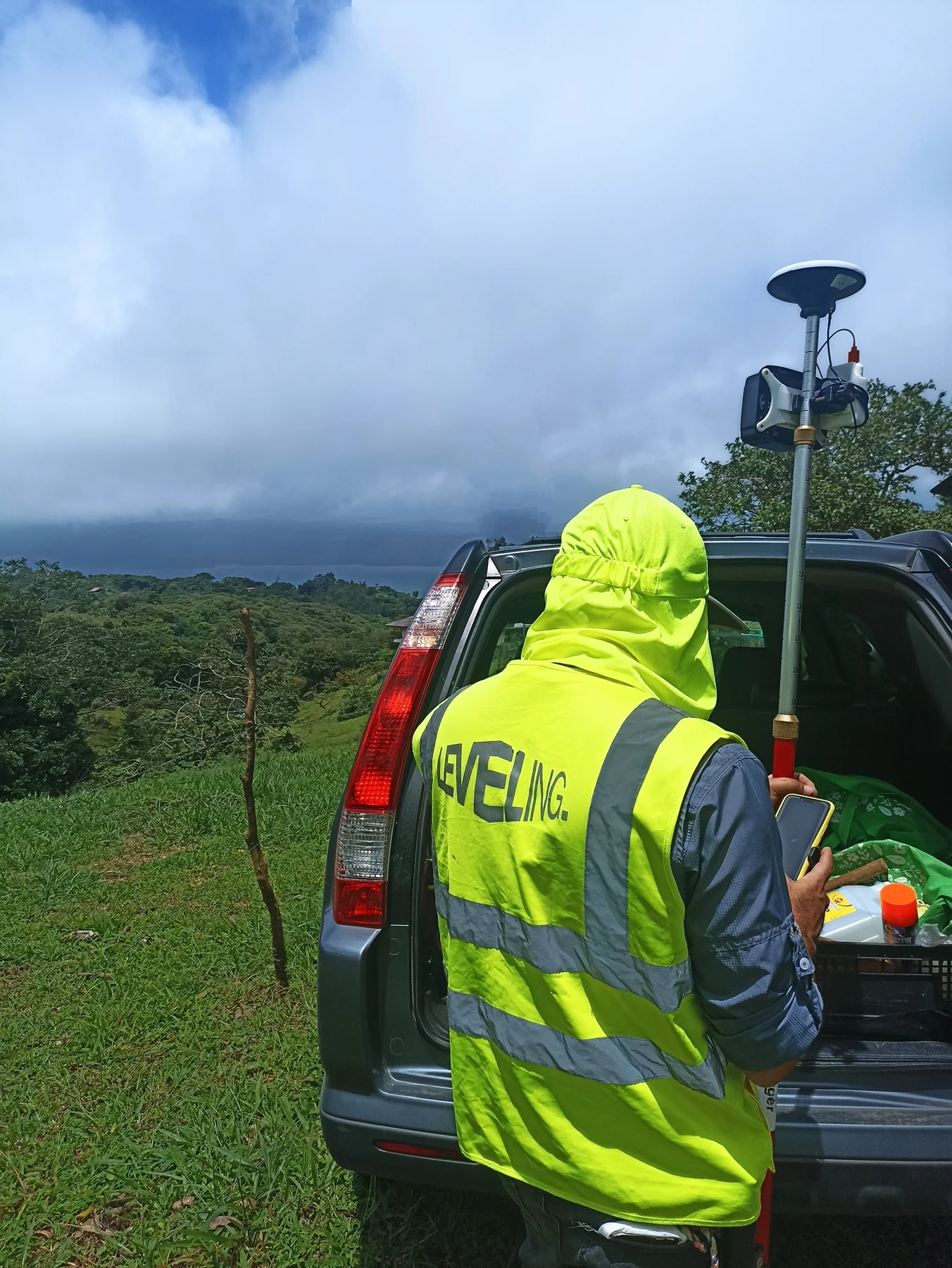 Leveling fieldwork with surveying equipment beside a vehicle